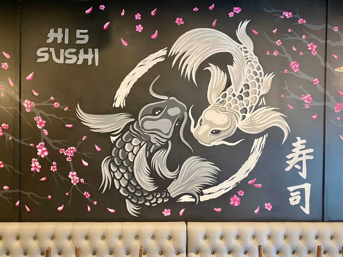 Hand-painted koi fish mural at Hi 5 Sushi featuring two grayscale koi swimming in a circular motion with pink cherry blossoms on a black wall.